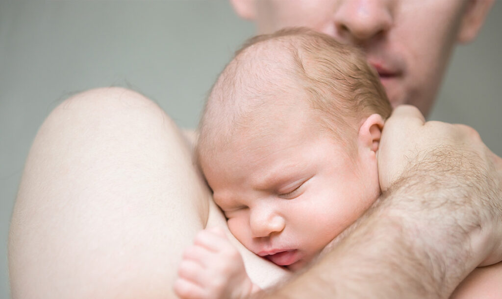 Vater hält schlafendes Baby im Arm