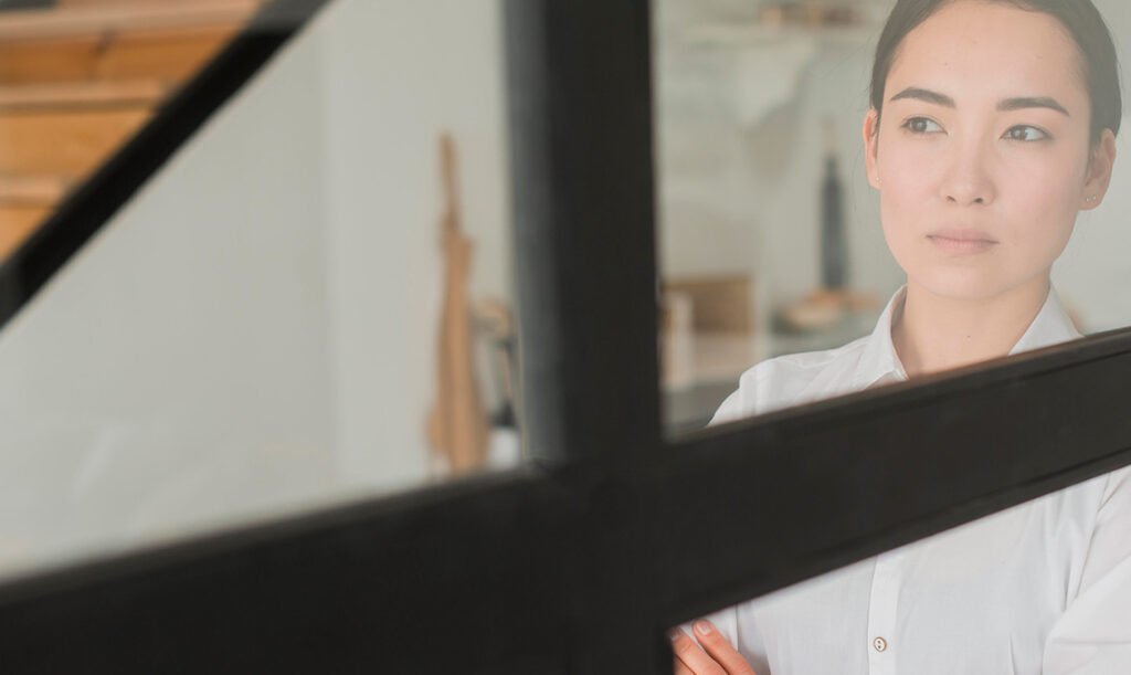 Frau nachddenklich aus dem Fenster schauend - symbolisch für Fachpersonal im sozialen Berufen